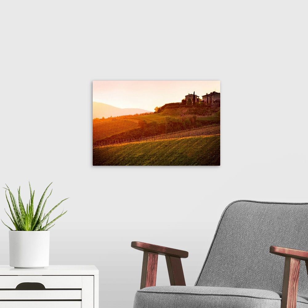 A modern room featuring The setting sun shines its last rays over a picturesque villa and its fields in this photo of Tus...