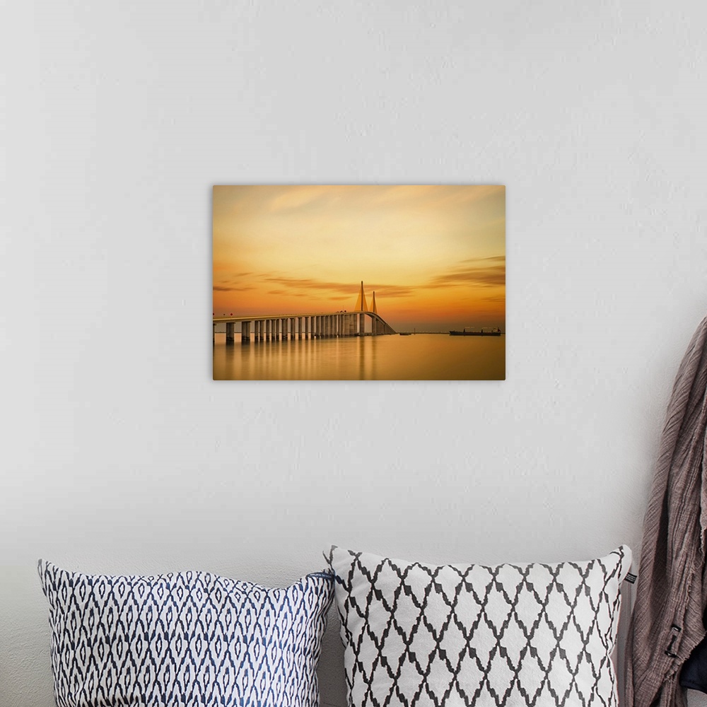 A bohemian room featuring Photograph of overpass crossing water at sunrise under a cloudy sky.
