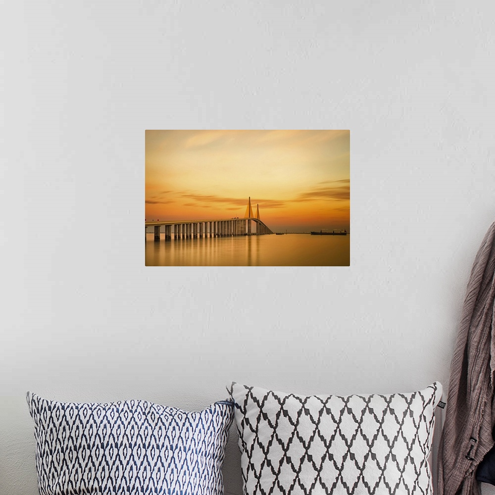A bohemian room featuring Photograph of overpass crossing water at sunrise under a cloudy sky.