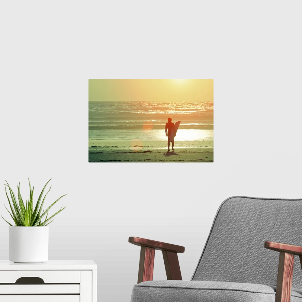 A modern room featuring Big print on canvas of a surfer with a surfboard silhouetted against the setting sun looking out ...