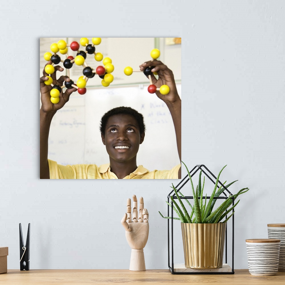 A bohemian room featuring African teenage boy viewing molecule model