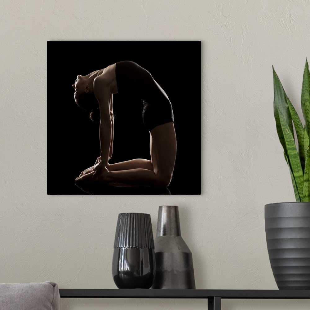 A modern room featuring Studio shot of young woman practicing yoga.   The camel pose, Ushtra asana.