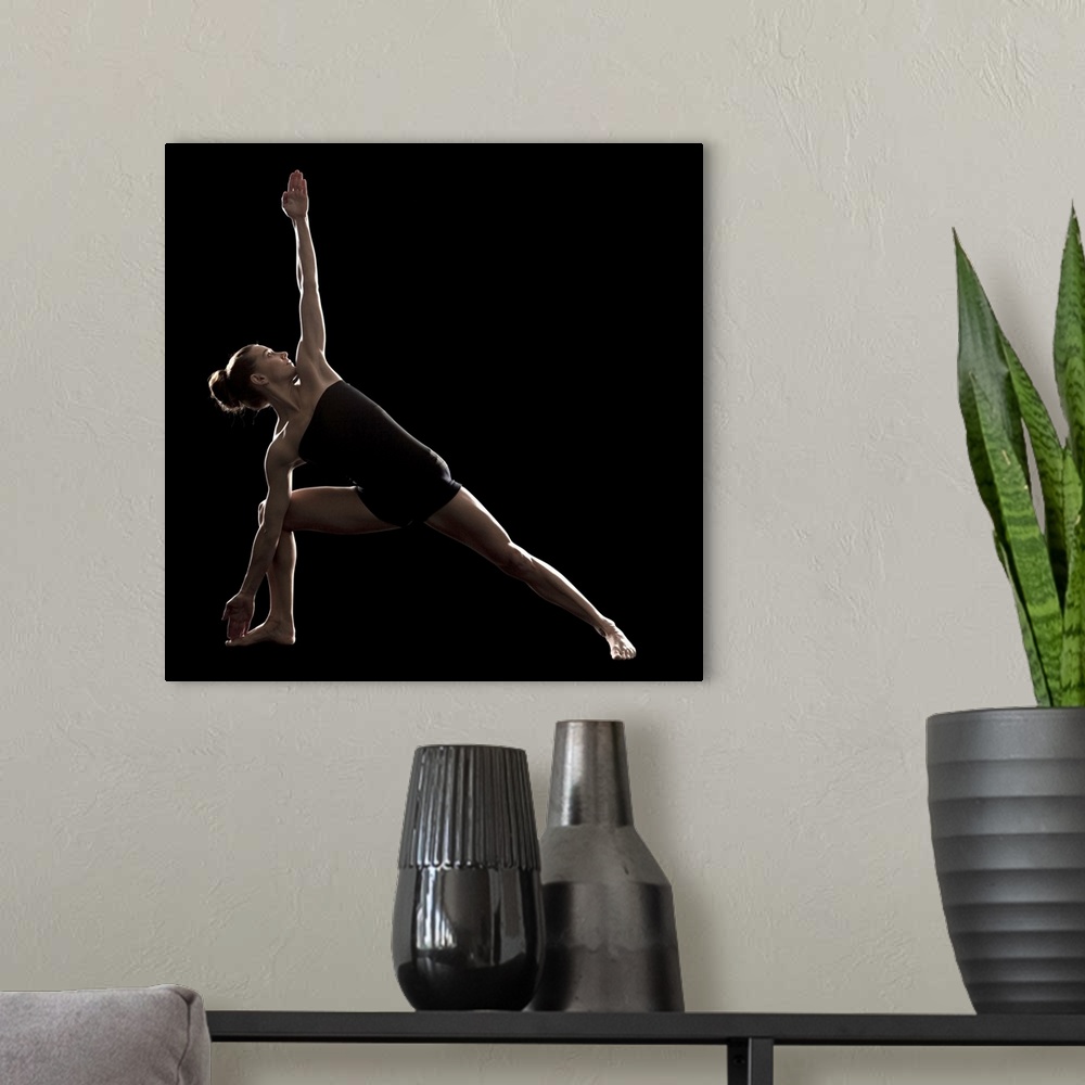 A modern room featuring Studio shot of young woman practicing yoga.  The extended side angle pose, utthita parsvakonasana.