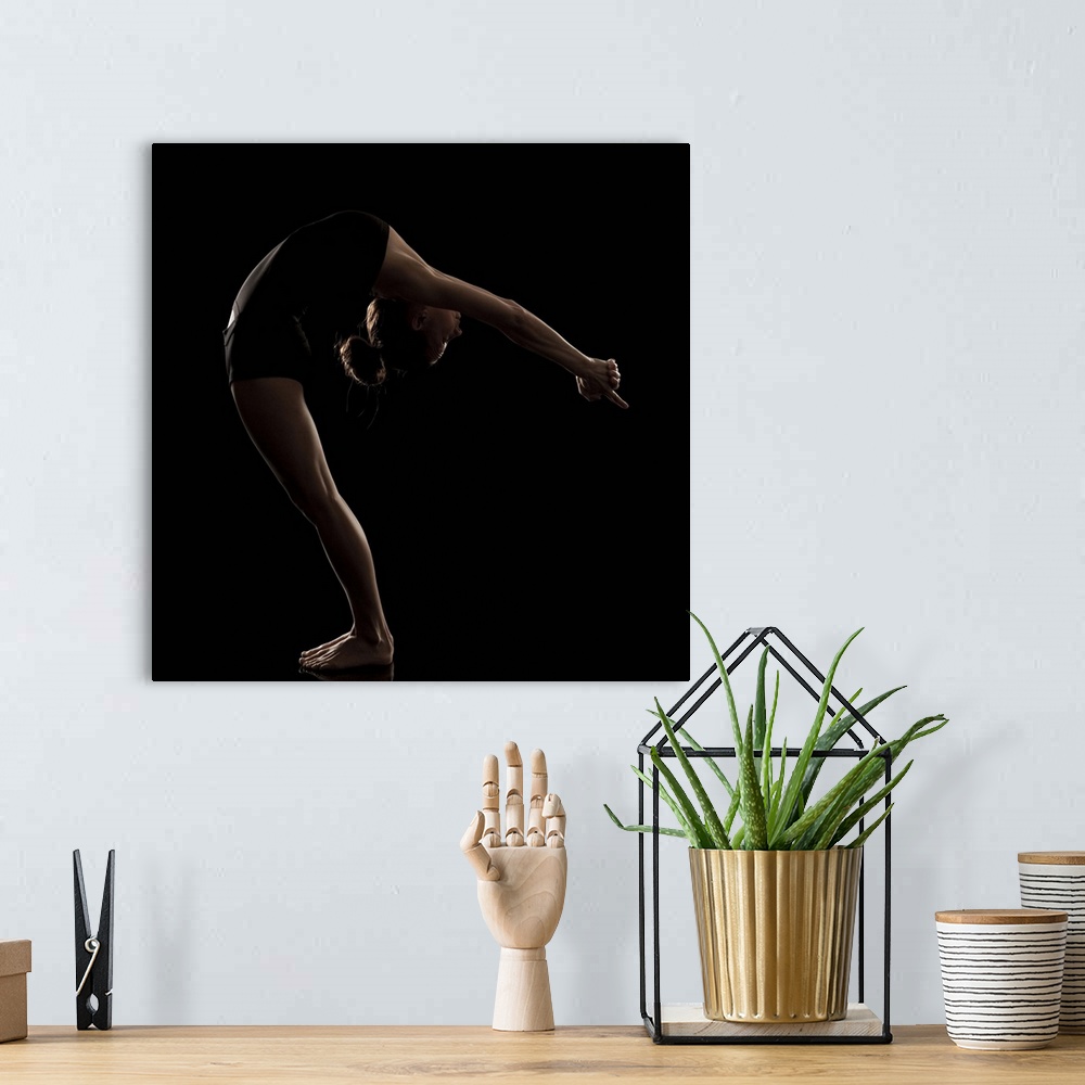 A bohemian room featuring Studio shot of young woman practicing yoga.  The half moon pose, ardha chandrasana.