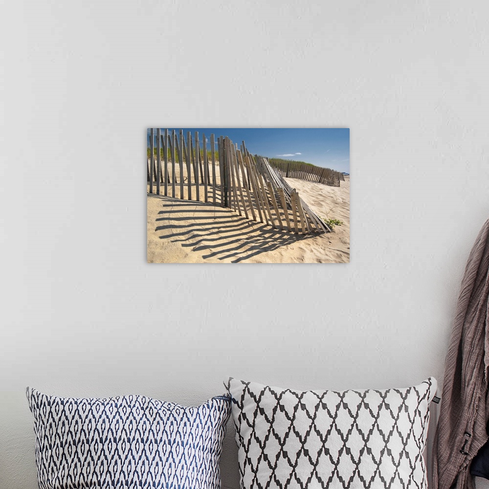 A bohemian room featuring The low sun casts long shadows of a wooden fence on a sandy dune by the ocean.