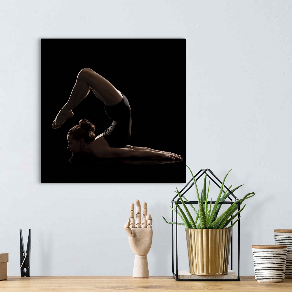 A bohemian room featuring Studio shot of young woman practicing yoga.  The scorpion pose, vrshikasana