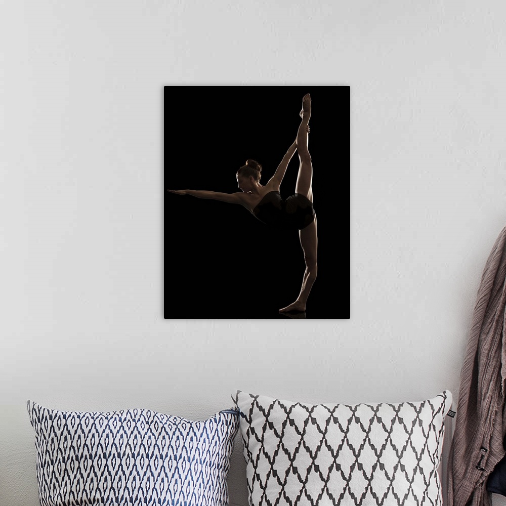 A bohemian room featuring Studio shot of young woman practicing yoga.  The standing bow pose, Dandayamana Dhanurasana.