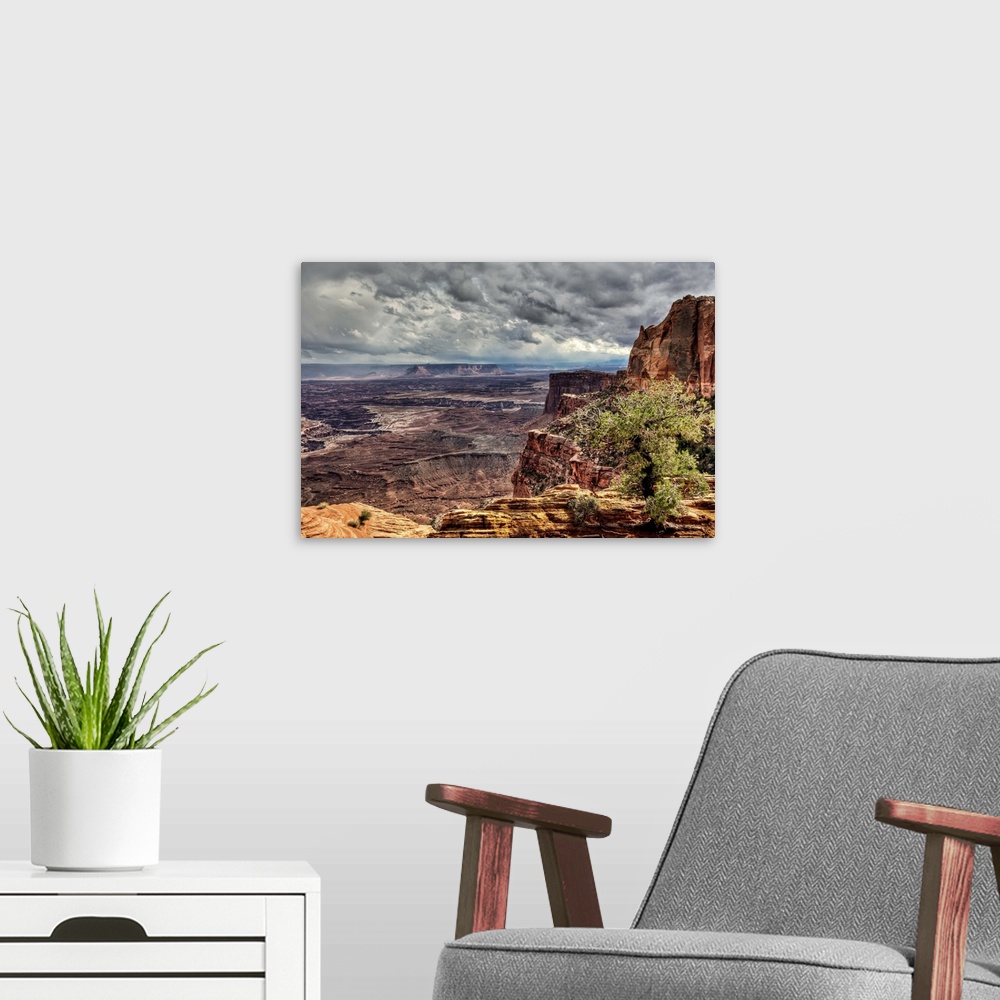 A modern room featuring A view near Mesa Arch into the vast Canyonlands National Park during a stormy day.  A rare rain s...