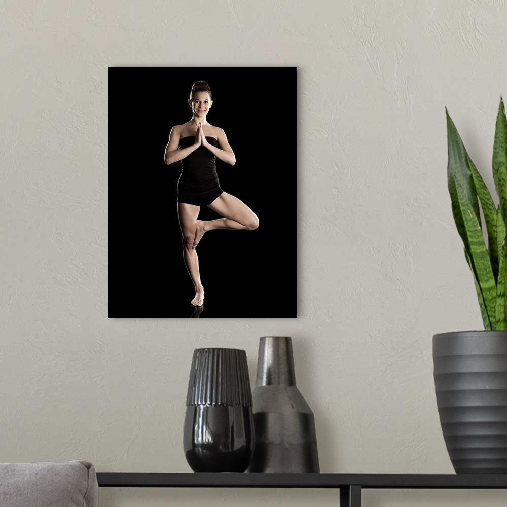 A modern room featuring Studio shot of young woman practicing yoga.  The tree pose, Vriksasana.
