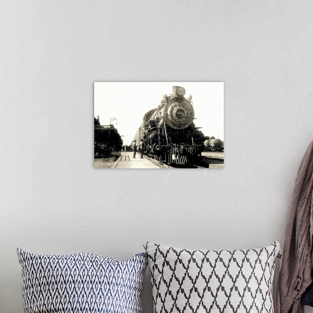 A bohemian room featuring This is a vintage photograph of a locomotive being admired by two men at a train station.
