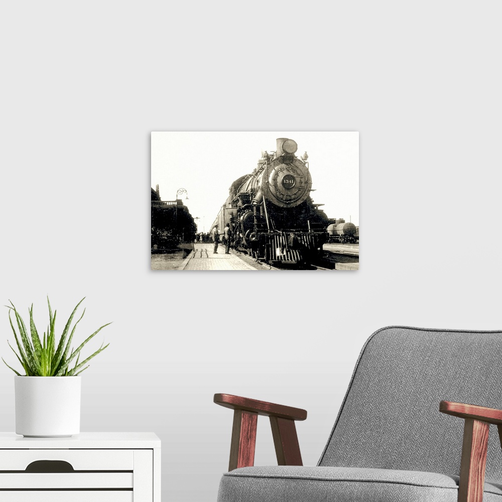 A modern room featuring This is a vintage photograph of a locomotive being admired by two men at a train station.