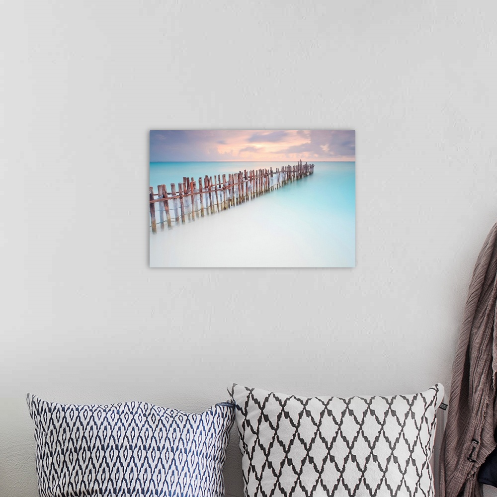 A bohemian room featuring Tranquil scene of Wooden posts in Caribbean sea, at sunset right after storm.