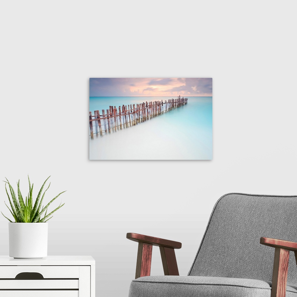A modern room featuring Tranquil scene of Wooden posts in Caribbean sea, at sunset right after storm.