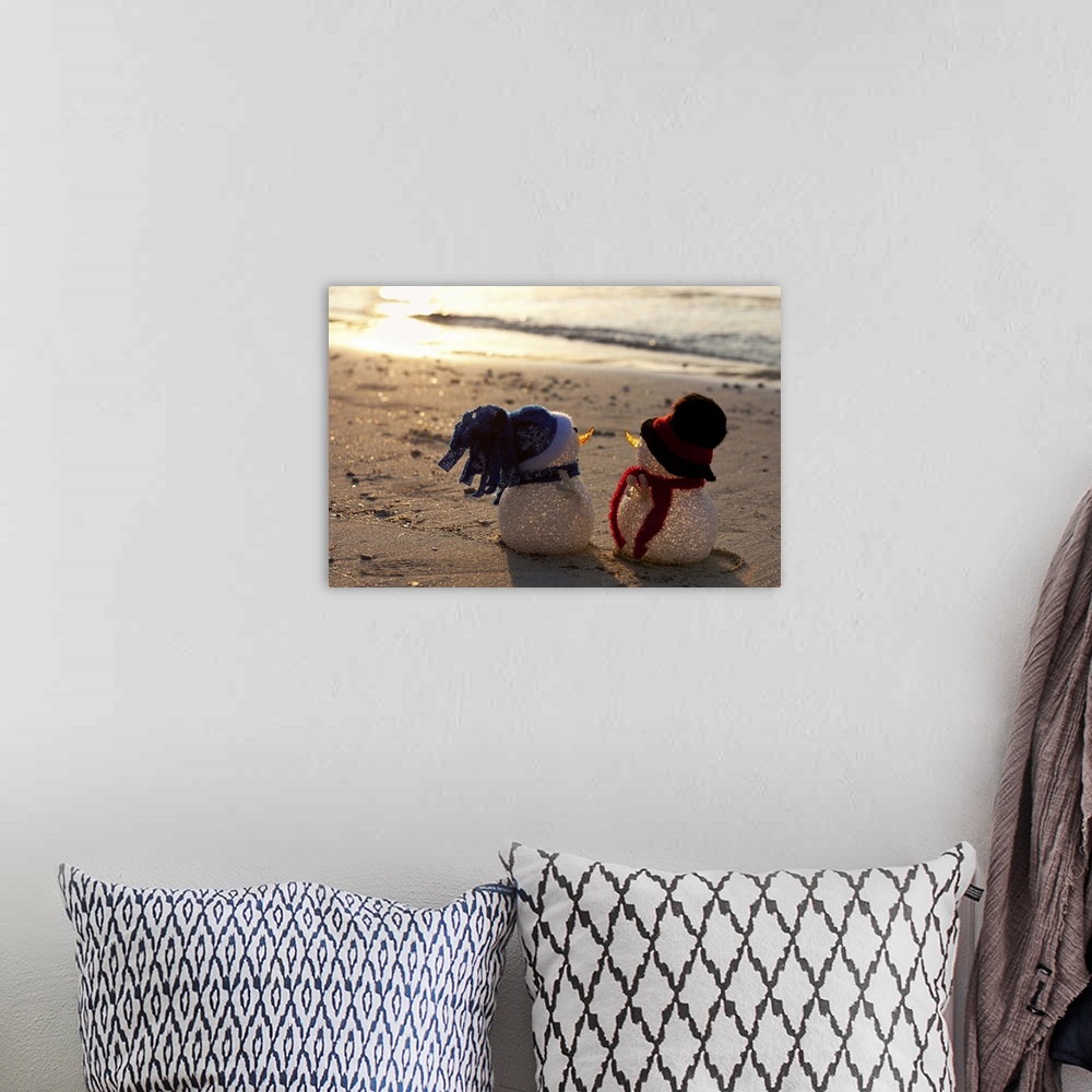 A bohemian room featuring Two snowmen look to the sea at sunset. White sand and waves in the background. View from behind. ...