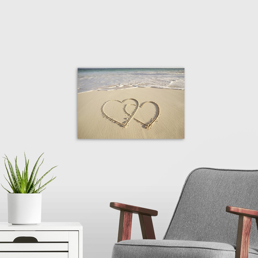 A modern room featuring Two overlying hearts drawn on the beach with incoming surf.