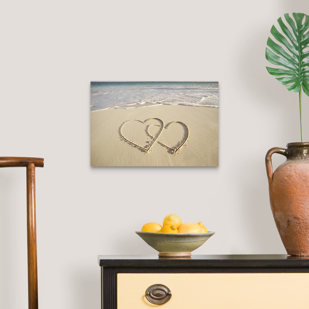 A traditional room featuring Two overlying hearts drawn on the beach with incoming surf.