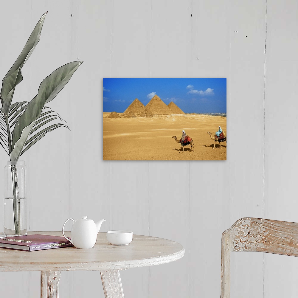 A farmhouse room featuring Two people riding camels near the pyramids of Giza, Egypt