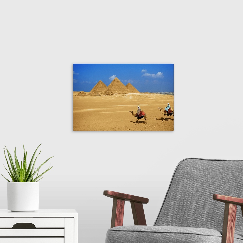 A modern room featuring Two people riding camels near the pyramids of Giza, Egypt