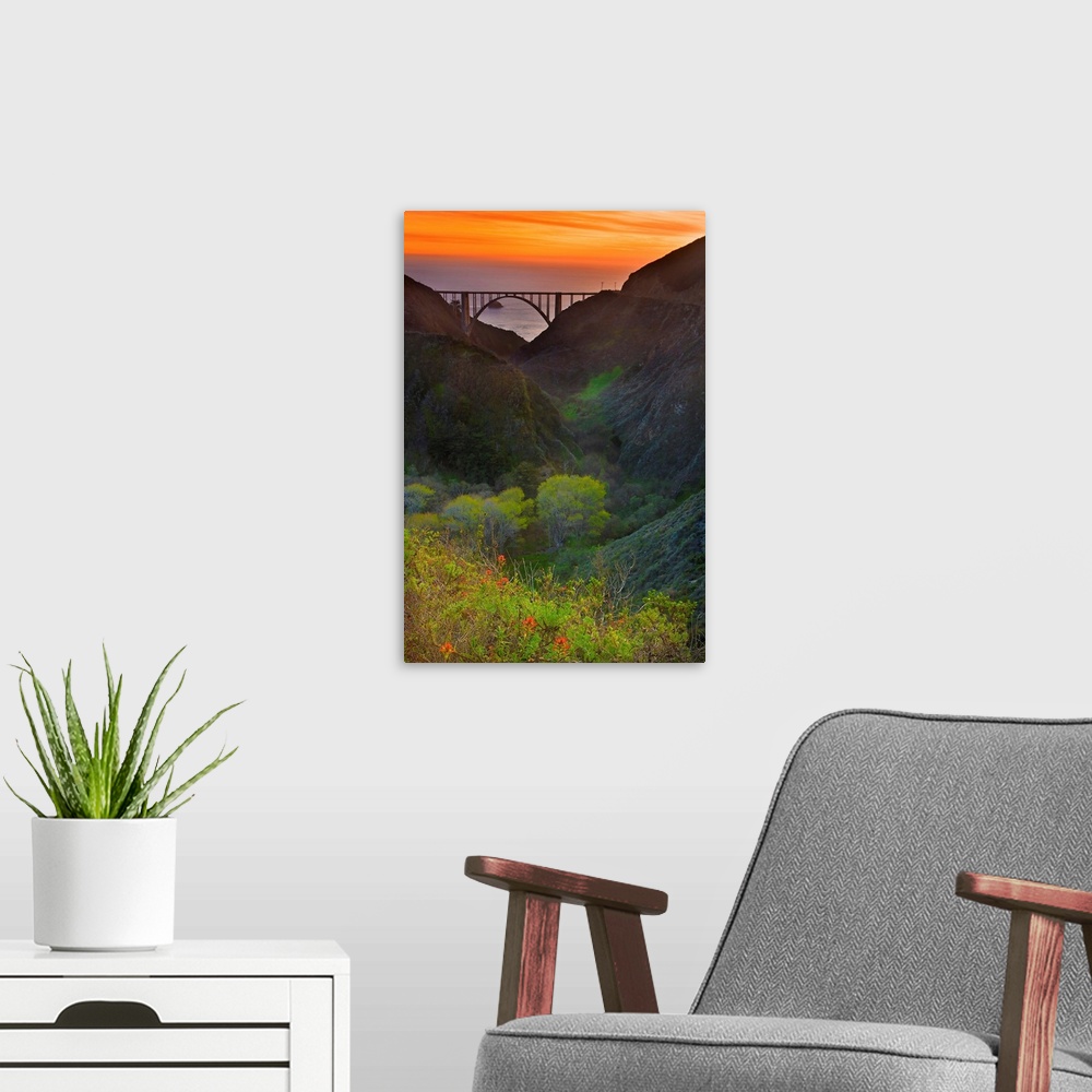 A modern room featuring Portrait oriented photo of the Big Sur bridge at sunset with rolling hills in the foreground and ...