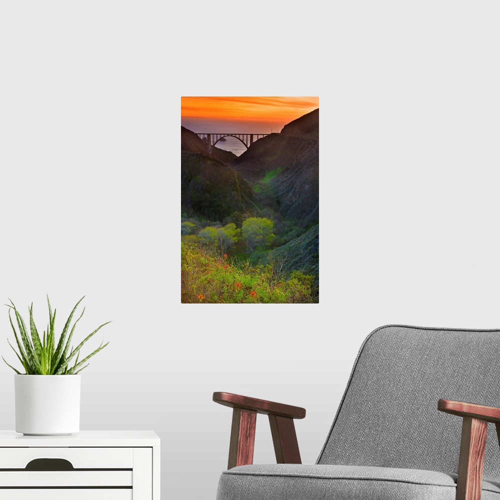 A modern room featuring Portrait oriented photo of the Big Sur bridge at sunset with rolling hills in the foreground and ...
