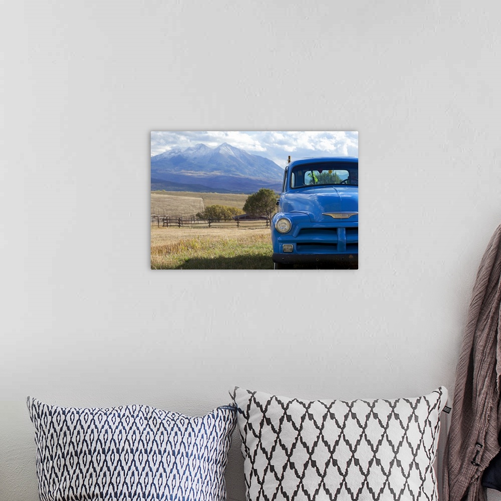 A bohemian room featuring Landscape, large photograph of part of the front of a blue, vintage truck, parked in a grassy fie...