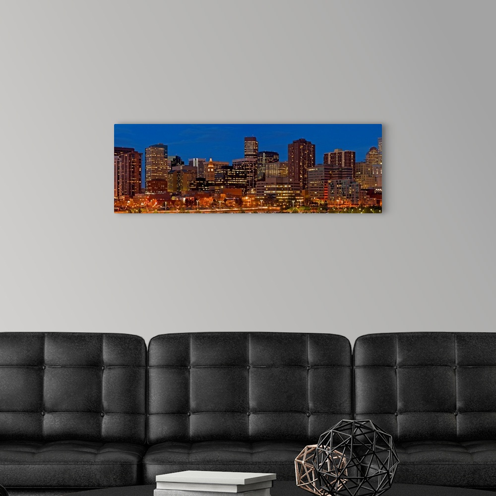 A modern room featuring Panoramic photograph of lit up skyline under a clear sky.