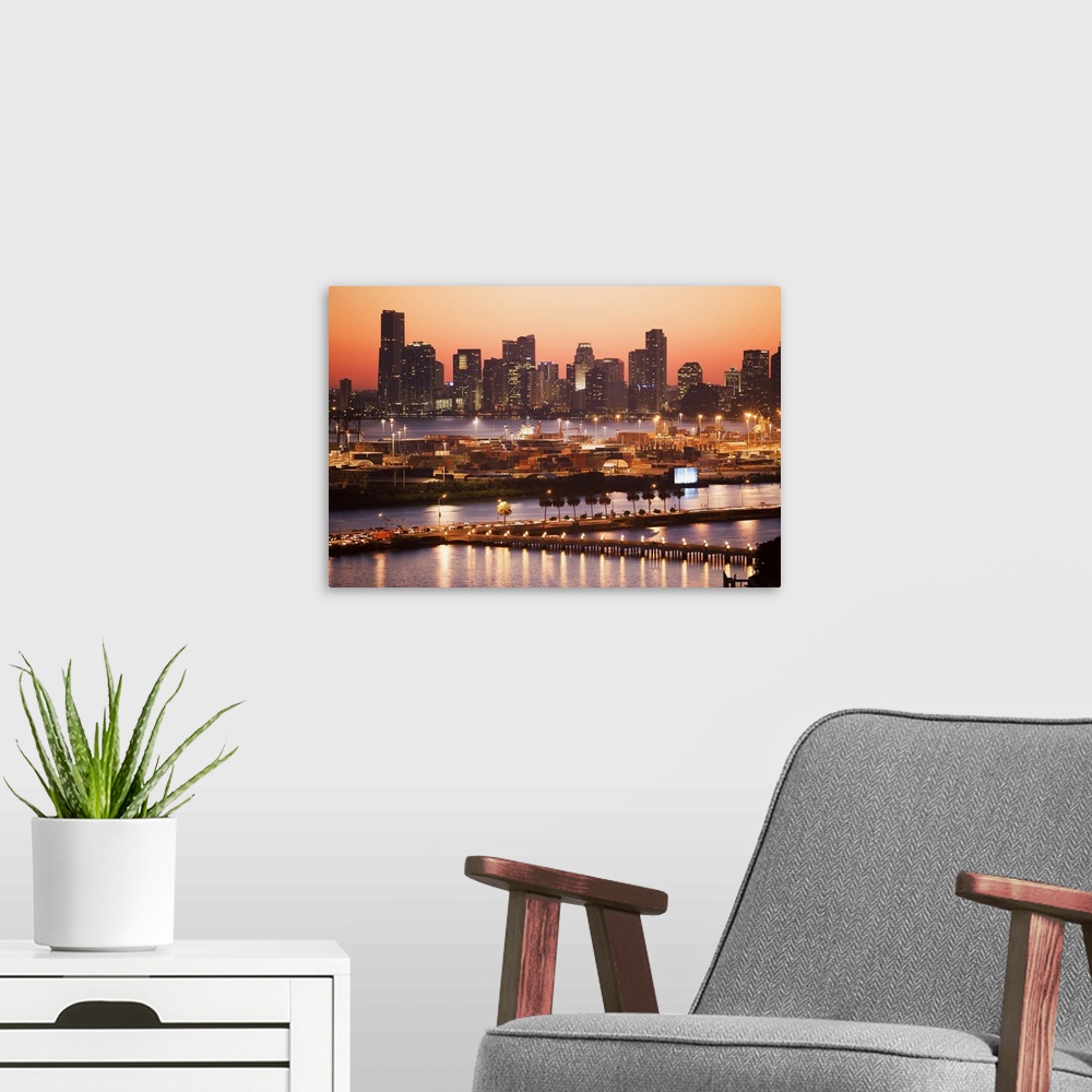 A modern room featuring Photograph of skyline and waterfront with buildings lit up at dusk.