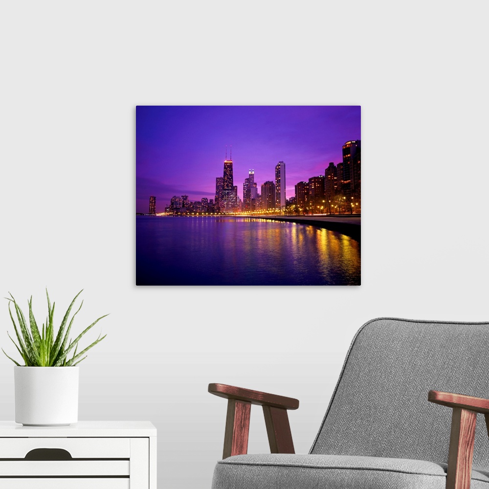 A modern room featuring Photograph of cityscape and waterfront at night.  The buildings are lit up and the lights are ref...