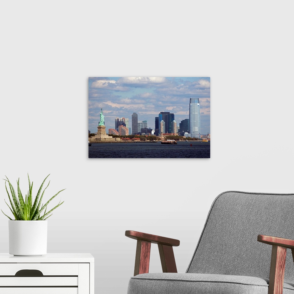 A modern room featuring The Statue of Liberty and the NYC skyline are photographed under a cloudy sky.