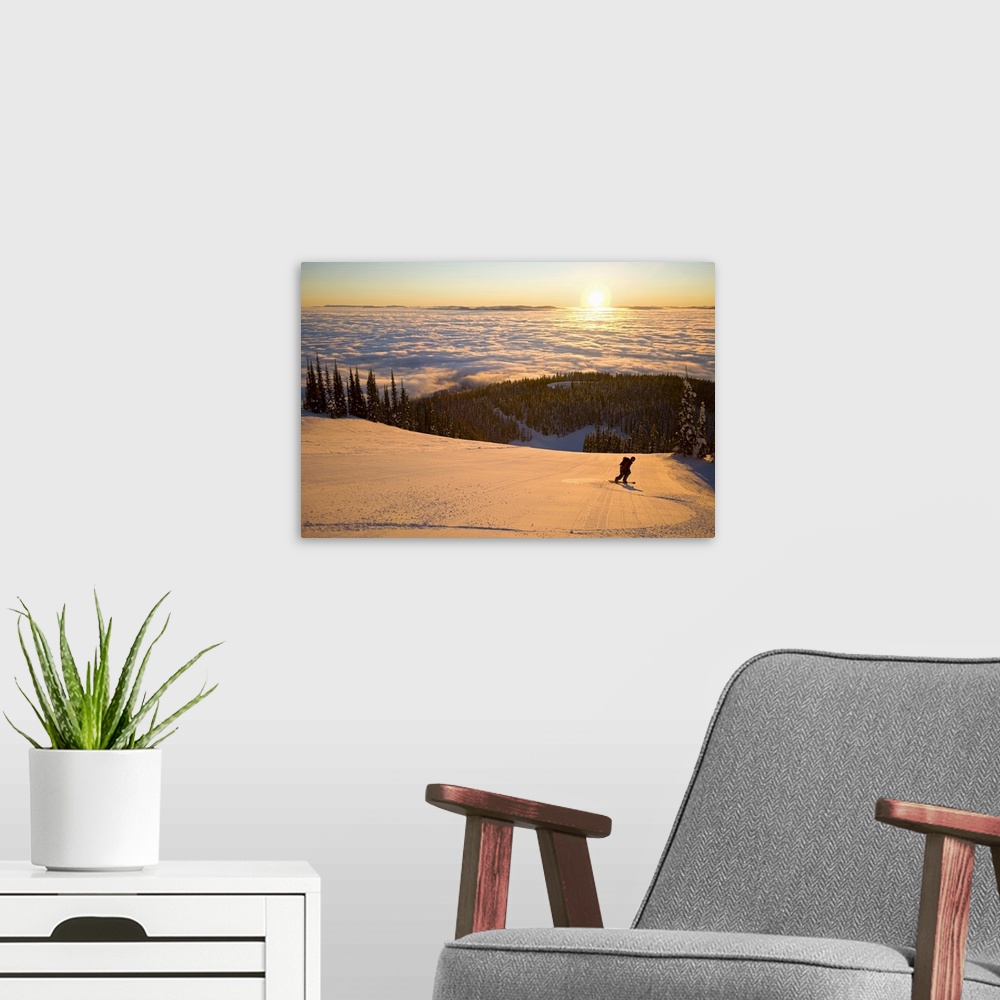 A modern room featuring Oversized horizontal photograph of a man snowboarding down a hill that is high above a winter lan...