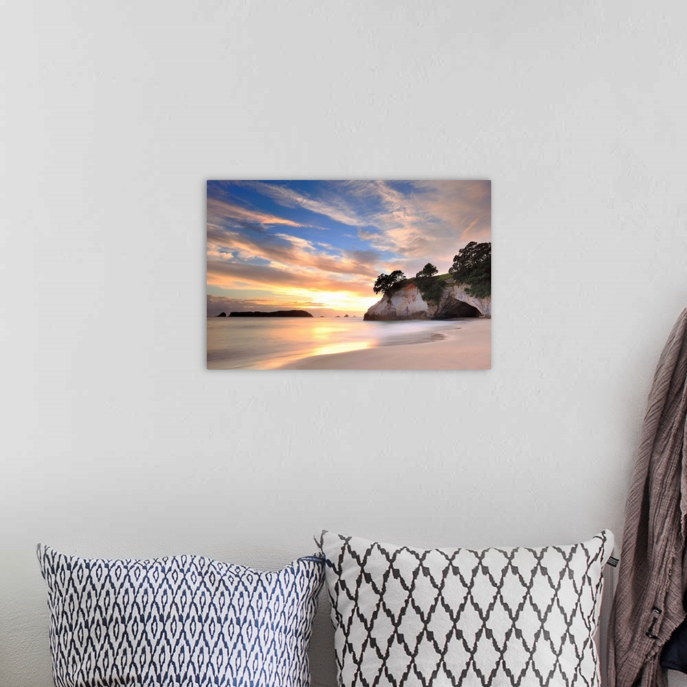 A bohemian room featuring Photograph of huge rock formation on beach under a cloudy sky.