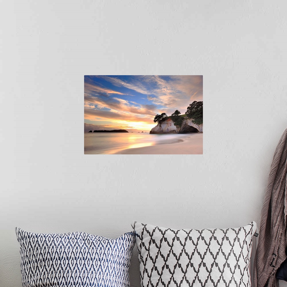A bohemian room featuring Photograph of huge rock formation on beach under a cloudy sky.