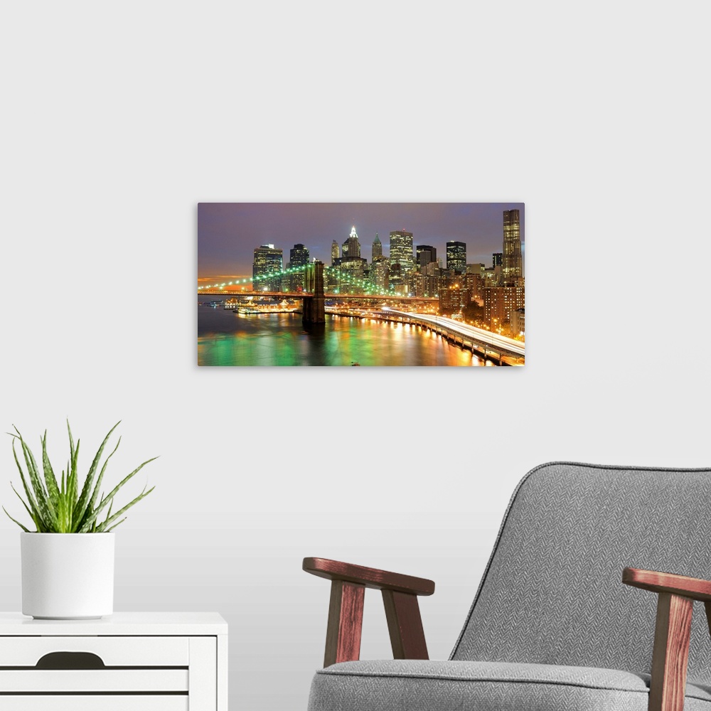 A modern room featuring Oversized, horizontal photograph of bright lights of the Brooklyn Bridge and New York City, at ni...