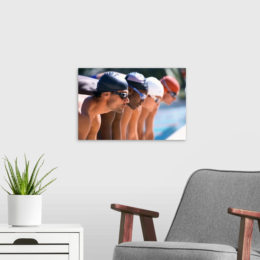 A modern room featuring view of male swimmers at the start of a race