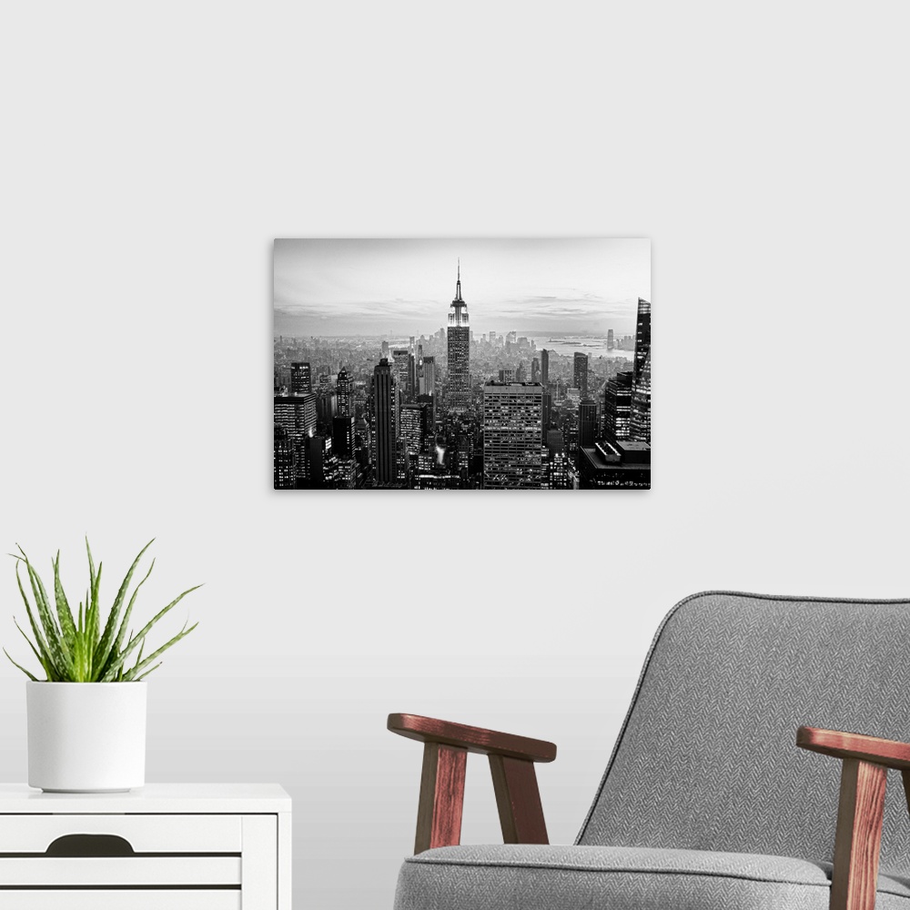 A modern room featuring High angled photograph of city buildings at dusk.  The building windows are filled with light cre...