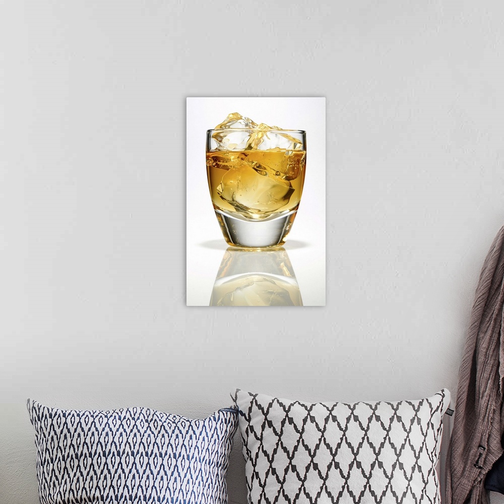 A bohemian room featuring Bourbon whiskey with three ice cubes in a low ball glass.