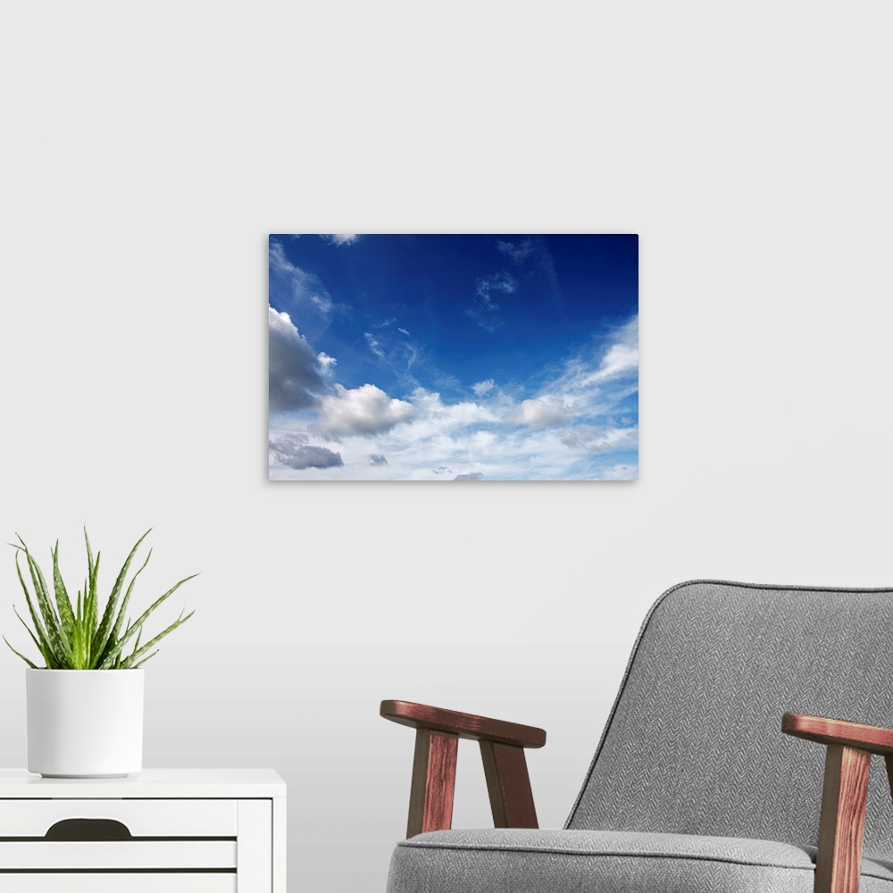 A modern room featuring Big canvas photo of lots of fluffy clouds in the sky.