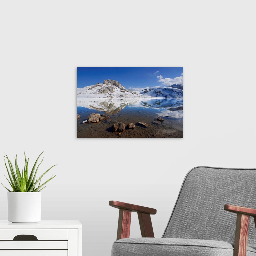 A modern room featuring Winter view of lakes of Covadonga, reflection of mountain on lake.