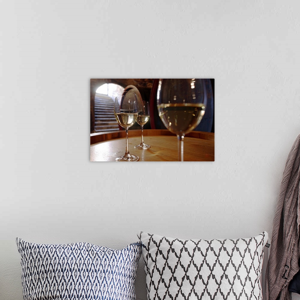 A bohemian room featuring Landscape, close up, large photograph of three glasses of white wine sitting on a wooden surface,...
