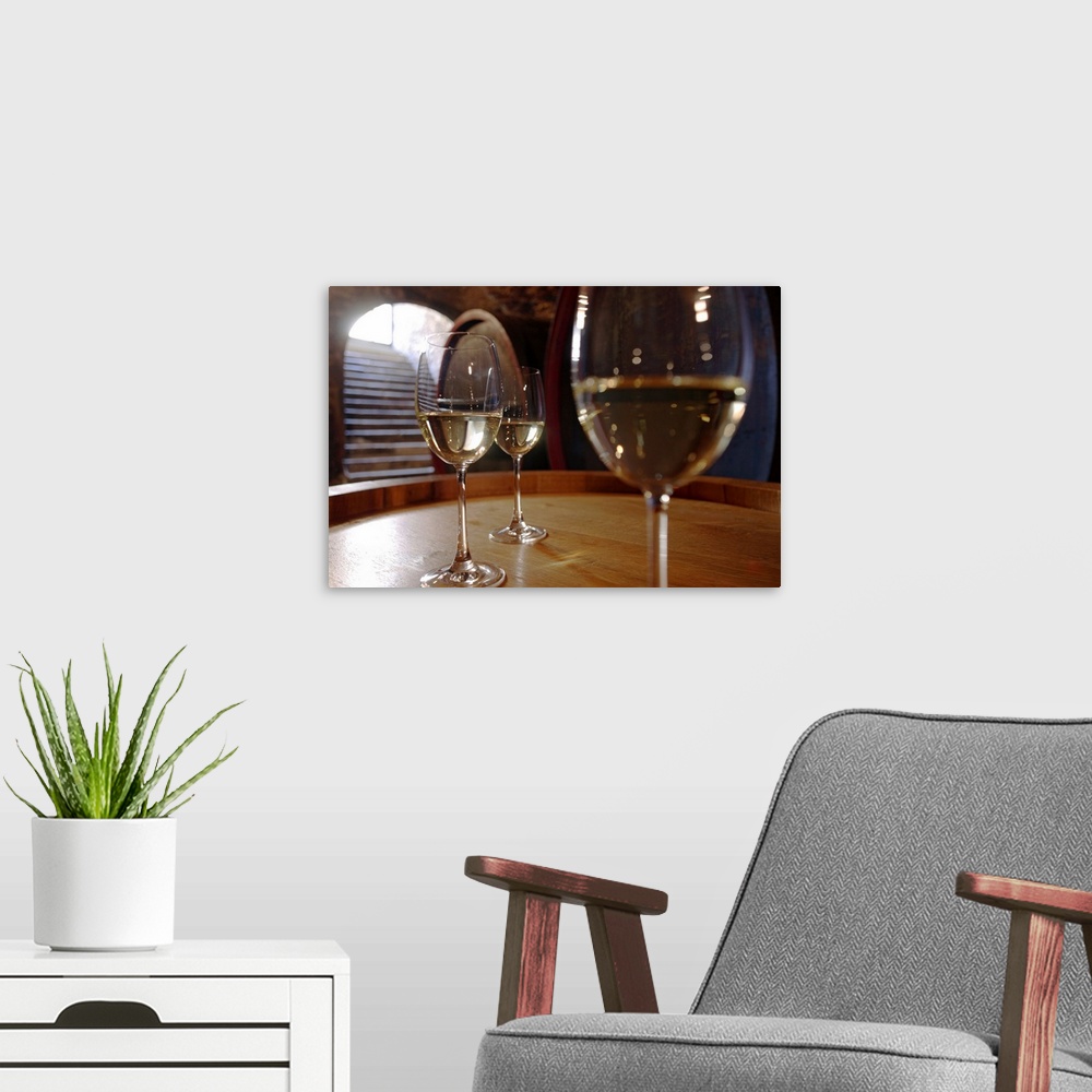 A modern room featuring Landscape, close up, large photograph of three glasses of white wine sitting on a wooden surface,...
