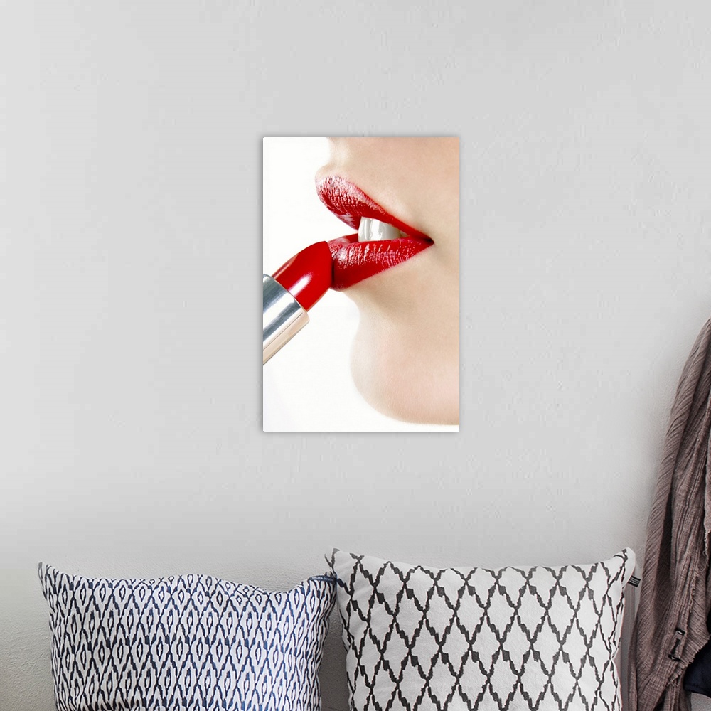A bohemian room featuring Up-close photograph of lady putting on colored lip balm from a tube.