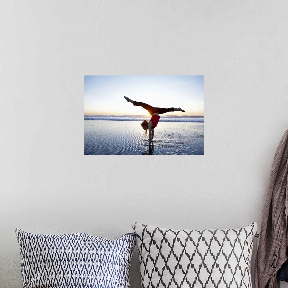 A bohemian room featuring Woman doing a hand-stand on the beach at sunset.