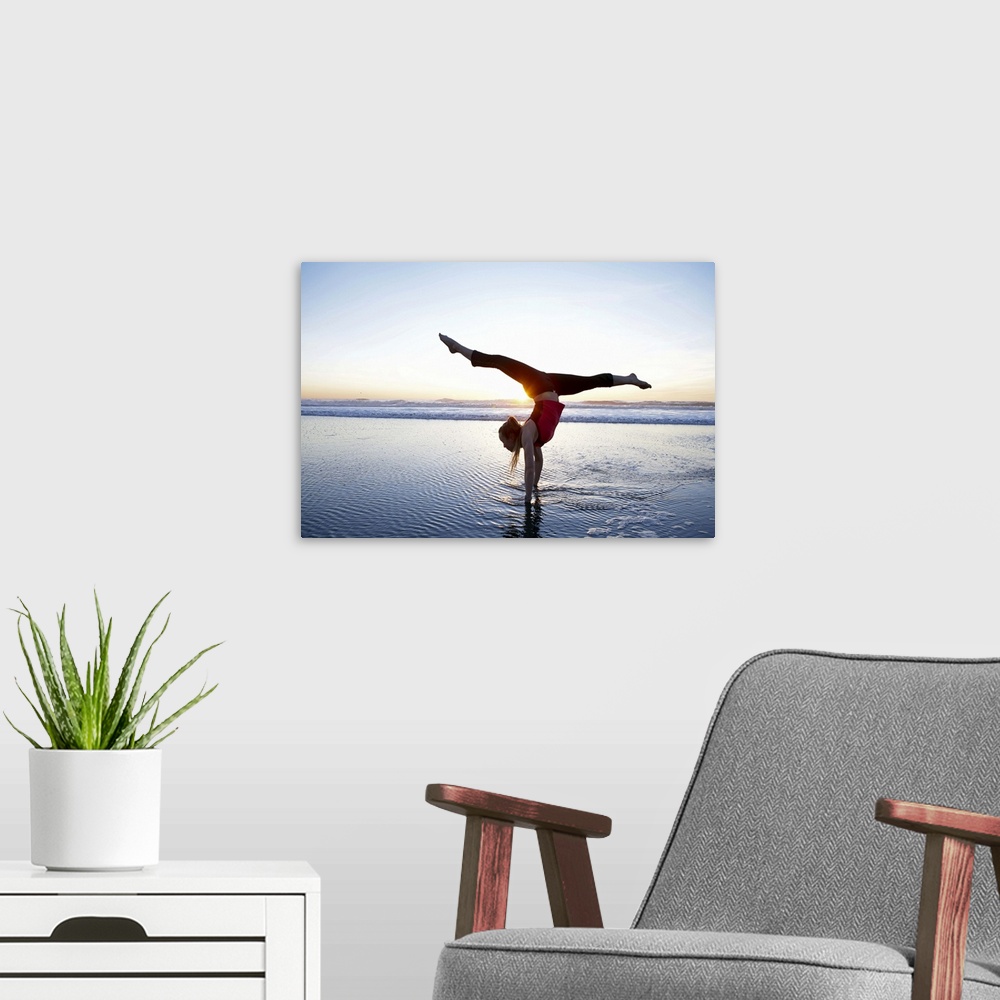 A modern room featuring Woman doing a hand-stand on the beach at sunset.