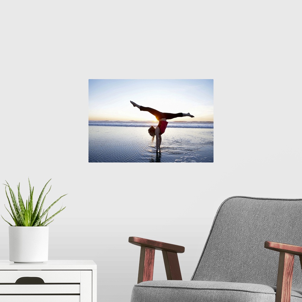 A modern room featuring Woman doing a hand-stand on the beach at sunset.