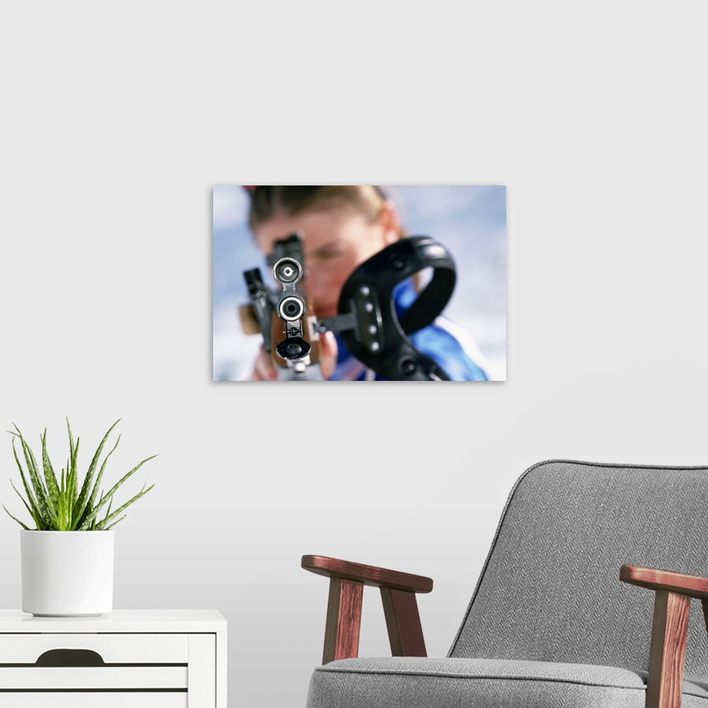 A modern room featuring Woman shooting rifle in biathlon (focus on nozzle)