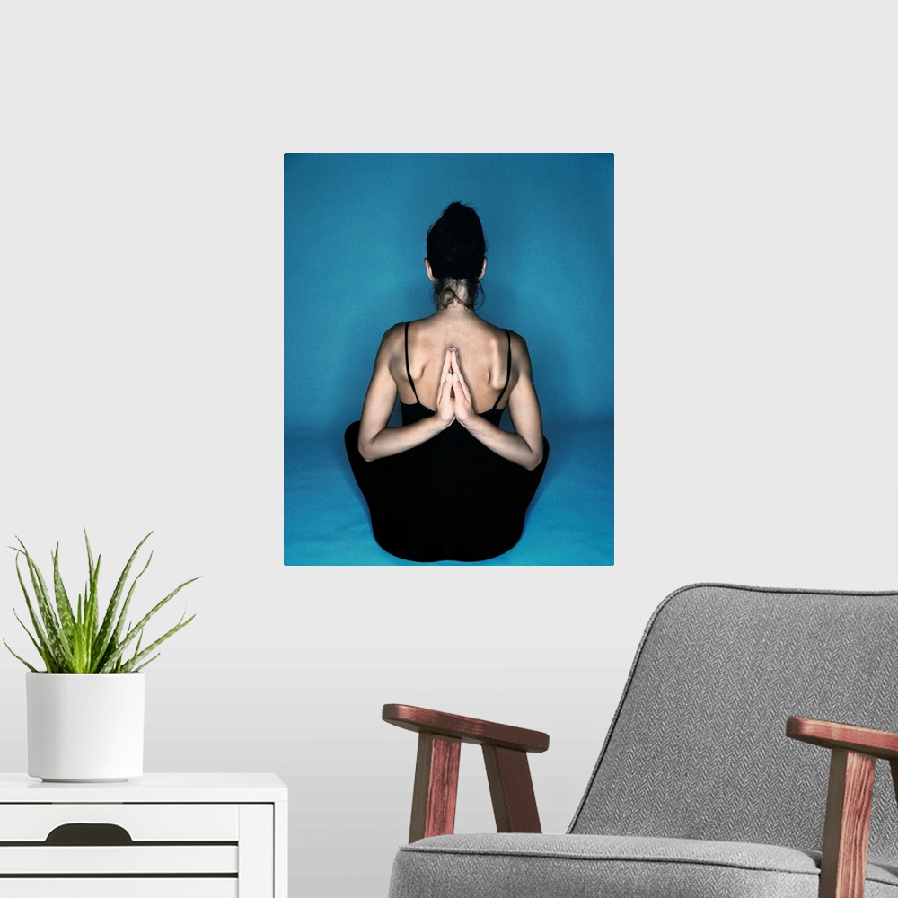 A modern room featuring Woman sitting in yoga reverse prayer position
