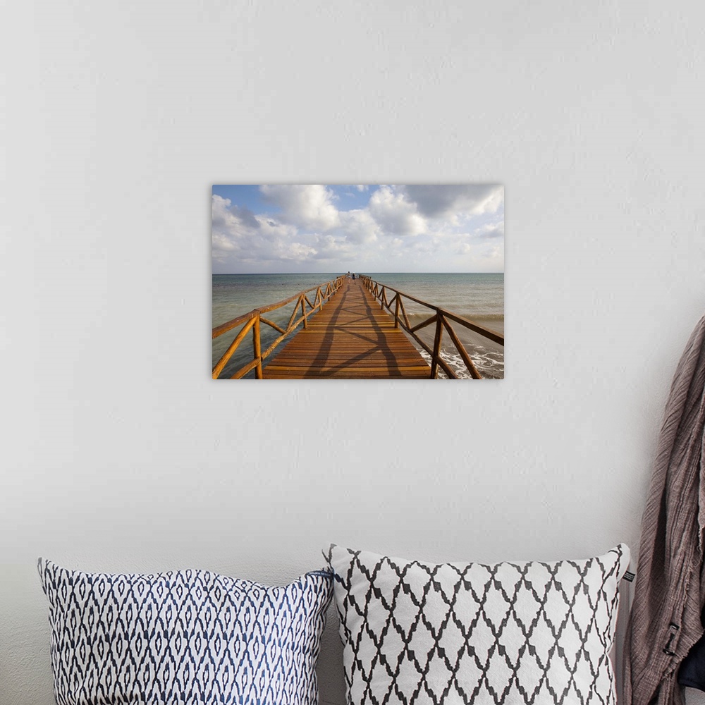 A bohemian room featuring People on rustic wood pier leading to Caribbean Sea horizon, Cancun, Mexico