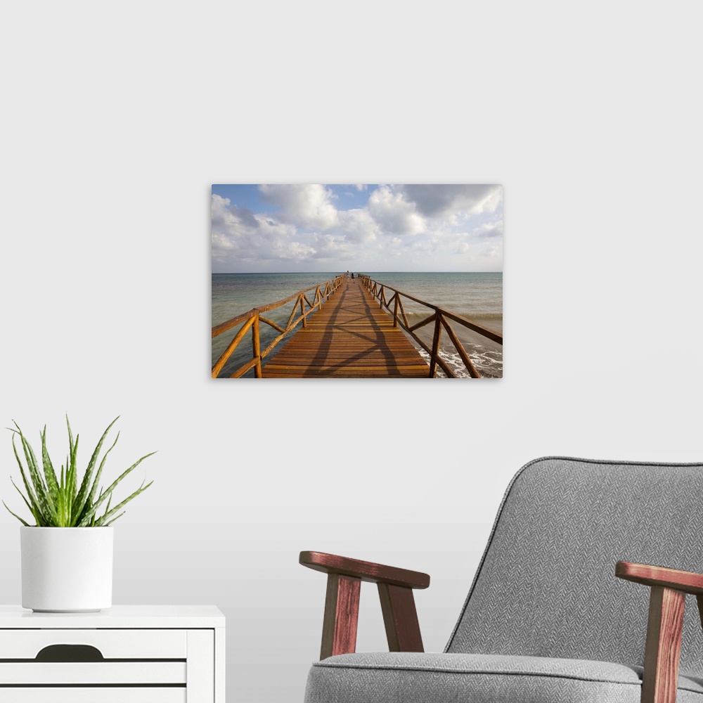 A modern room featuring People on rustic wood pier leading to Caribbean Sea horizon, Cancun, Mexico