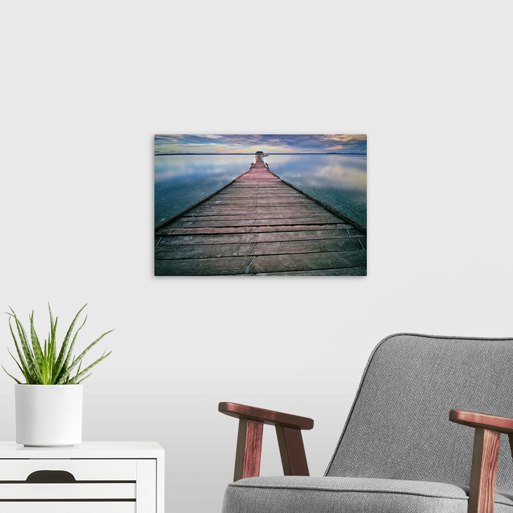 A modern room featuring Wall art of a long pier leading out into the calm water.