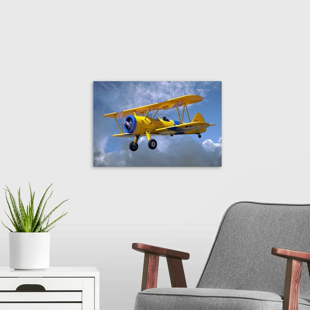 A modern room featuring Yellow Stearman 5YP bi-plane flying in cloudy sky